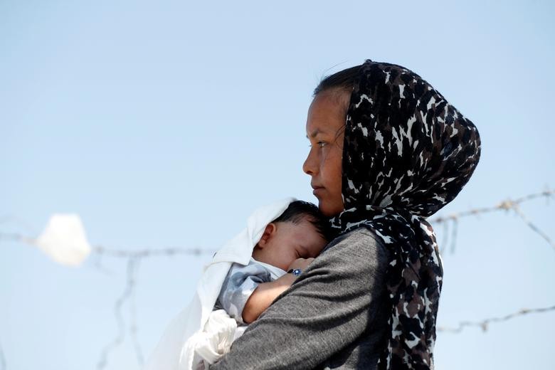 An Afghan woman and her month-old son are seen outside the new temporary camp for migrants and refugees, on the island of Lesbos, Greece, September 21, 2020. REUTERS/Yara Nardi